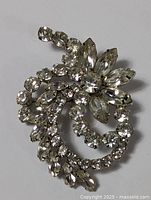 Top view of the Weiss vintage rhinestone pin brooch showing swirl and flower design with round and marquise clear rhinestones in silver-tone metal setting.