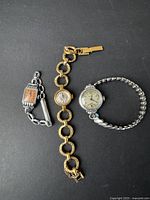 Three vintage women's Swiss made wristwatches with different styles and metal bands placed side by side on a black background.