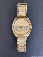 Front view of vintage men's Tradition Hasar Quartz wristwatch, gold-tone with day-date feature.