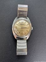 Full view of vintage Hillmans men's watch with metal expansion band, showing overall worn condition and silver-tone stainless steel case.