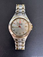 Front view of vintage Wenger men's wristwatch featuring stainless steel and gold-tone bracelet and silver dial with date.