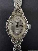 Close-up of watch face showing Dynasty logo, 17 jewels, manual wind crown, and intricate ornamental bezel pattern.