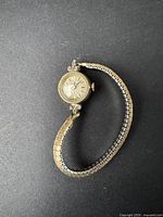 Full view of the vintage women's Caravelle wristwatch with silver-tone metal expandable band on a dark background.