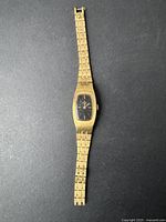 Full view of the vintage Elgin gold-tone watch on black background, showing the rectangular case and linked metal band.