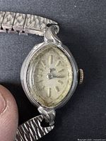 Close-up image of the watch face showing the oval dial marked 'Elgin'. The glass face shows some dirt and wear. Silver-tone metal case and crown.