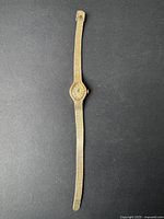 Full view of the vintage women's Gruen watch showing gold-tone textured metal strap and oval watch face.