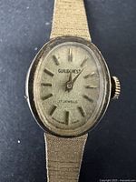 Close-up of watch face showing Guildcrest branding, 17 jewels marking, gold-tone oval dial and gold-tone hour markers.