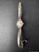 Full view of vintage women's Caravelle wristwatch with textured silver-tone link bracelet and safety chain.