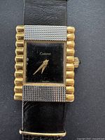 Close-up image of the rectangular watch face showing the black dial with gold hands and Catena branding on the dial, gold electroplated textured sides of the case, and black leather strap.