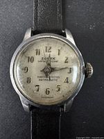 Close-up view of the Zonex watch dial showing signs of wear, discoloration, and numerals from 1 to 12 with hands indicating time and crown on the side for manual winding.