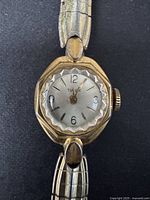 Close-up of the watch face showing Timex brand, faceted crystal, and gold-toned casing with watch hands and numerals.