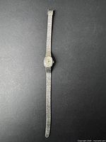 Full view of vintage silver-tone women's Timex watch with textured bracelet on black background.