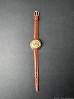 Full view of vintage women's Timex wristwatch laid out flat showing brown leather strap and gold-tone round case.