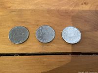 Front side (reverse) of three Canadian 1 dollar coins showing the designs: 1975 loon, 1983 caribou, 1986 two sailing ships.