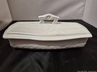 Top view of white covered butter dish showing embossed pattern on lid and geometric handle
