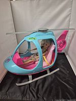 Front side view of Barbie helicopter toy with seated doll visible inside, showing color and design details
