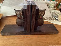 Front view of the pair of wooden cat bookends showing carved cat faces with whiskers and dark wood finish.
