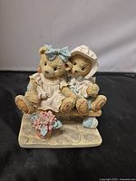 Front view of the Cherished Teddies figurine showing two bears seated together on a bench, with floral decoration at the base.