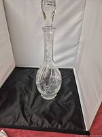 Full view of clear crystal decanter with stopper against white background
