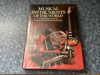 Front cover of the 'Musical Instruments of the World' illustrated encyclopedia book showing various musical instruments and title text.