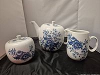 Photo of Royal Worcester Rhapsody teapot, creamer, and sugar bowl showing blue floral patterns on white ceramic.