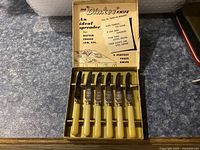 Set of six Dinkee spreader knives in original box with branding and instructions inside lid.