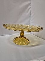 Side view showing the amber pedestal dish with scalloped edge and smooth glasswork.
