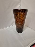 Full side view of the tall conical vintage handblown glass vase showing mottled amber and dark brown pattern.