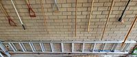 Full length view of aluminum extension ladder stored horizontally against wall