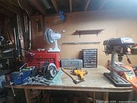 Overall lot on workbench showing drill press, toolboxes, vise, power drill, parts organizer