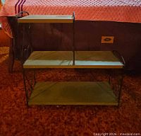 Front view showing three green shelves and black scrollwork frame