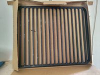 Front view of cast iron searing grill grate in cardboard sleeve
