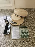 All four items: kitchen scale with lid, conversion calculator, pocket calculator with case, hourglass