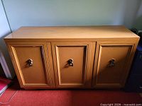 Front view showing three doors with metal pulls and plinth base