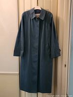 Full front view of blue trench coat on hanger