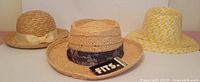 Three hats grouped: FITS fedora with tag, cloche with bow, yellow patterned sun hat