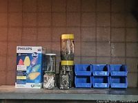 Boxed Philips LED C9 lights, four jars of fasteners, stack of blue bins