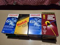 Top view of mixed sealed VHS tapes showing Maxell, Kodak, Memorex packaging