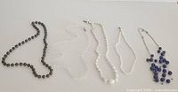 Five beaded necklaces laid out side by side showing design, color, and closures