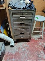 Front view of metal tool chest showing all six drawers and castors