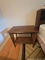 Front view of walnut veneer end table showing lower shelf and tapered legs