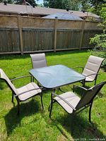 Full view of table and four chairs arranged on lawn