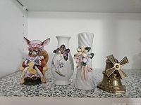 Group shot of four decorative items: bunny figurine, two vases, brass windmill