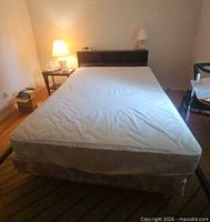 Full view of assembled queen bed with mattress, box spring, headboard