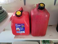Front view of both red plastic 2.5 gal gas cans showing labels and caps