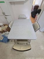 Top view of table and chairs showing laminate surface, chrome legs, chair upholstery condition
