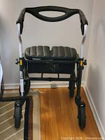 Front view of rollator showing seat, basket, wheels, brakes