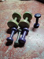 Six dumbbells arranged on floor showing colors, coatings and wear