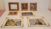 Seven framed items displayed on surface: three gold frames (two with prints, one empty), one tan-matted ballet print, three white frames with landscape prints