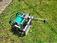 Hose reel with teal hose lying on grass
